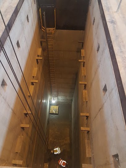 Deep rectangular shaft lined with concrete panels, viewed from above