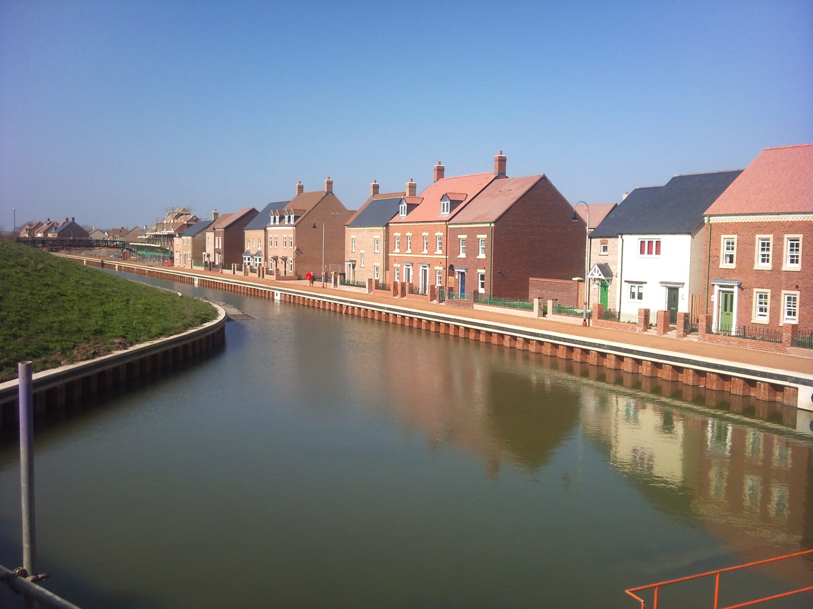 Completed sheet-pile retaining walls lining a canal beside newly built homes