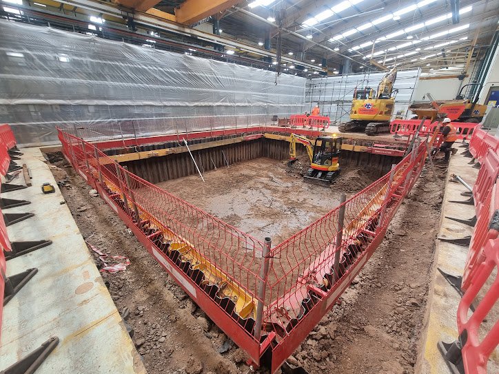 Sheet-supported excavation with a small excavator inside an industrial building