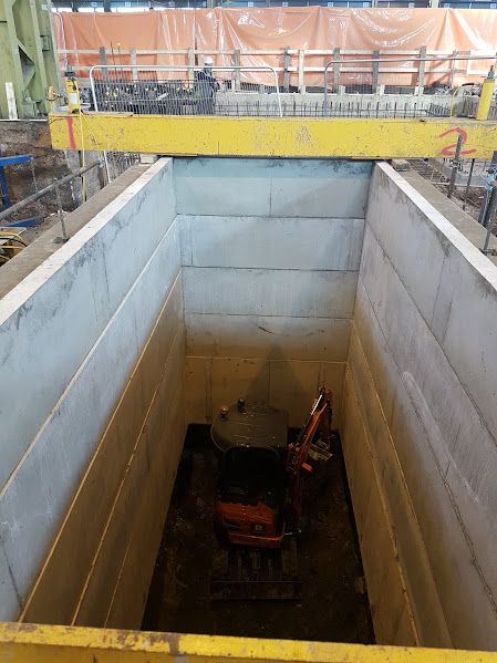 Rectangular shaft with mini excavator at depth