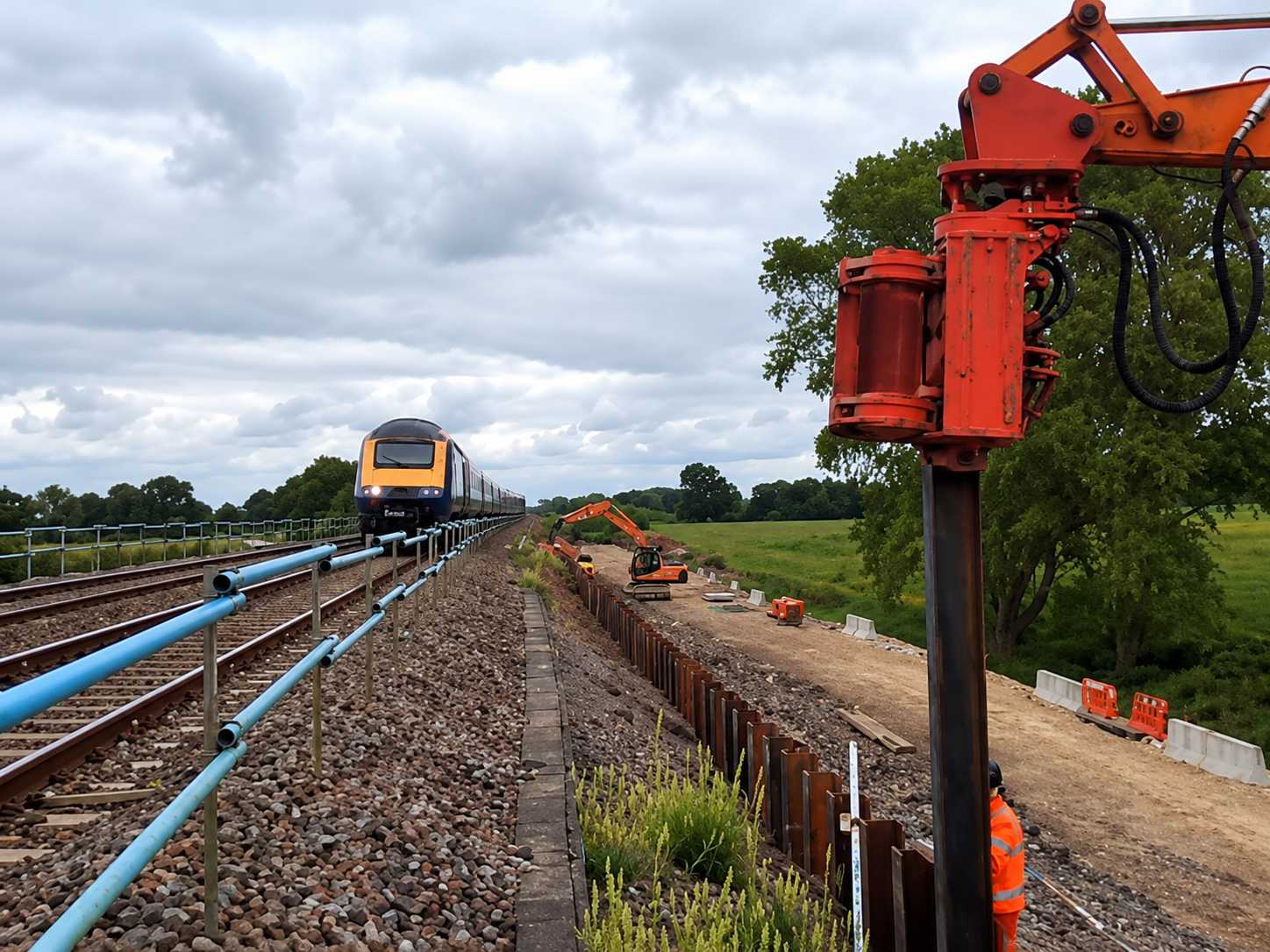 Passenger train passing beside the H-beam and piling hammer