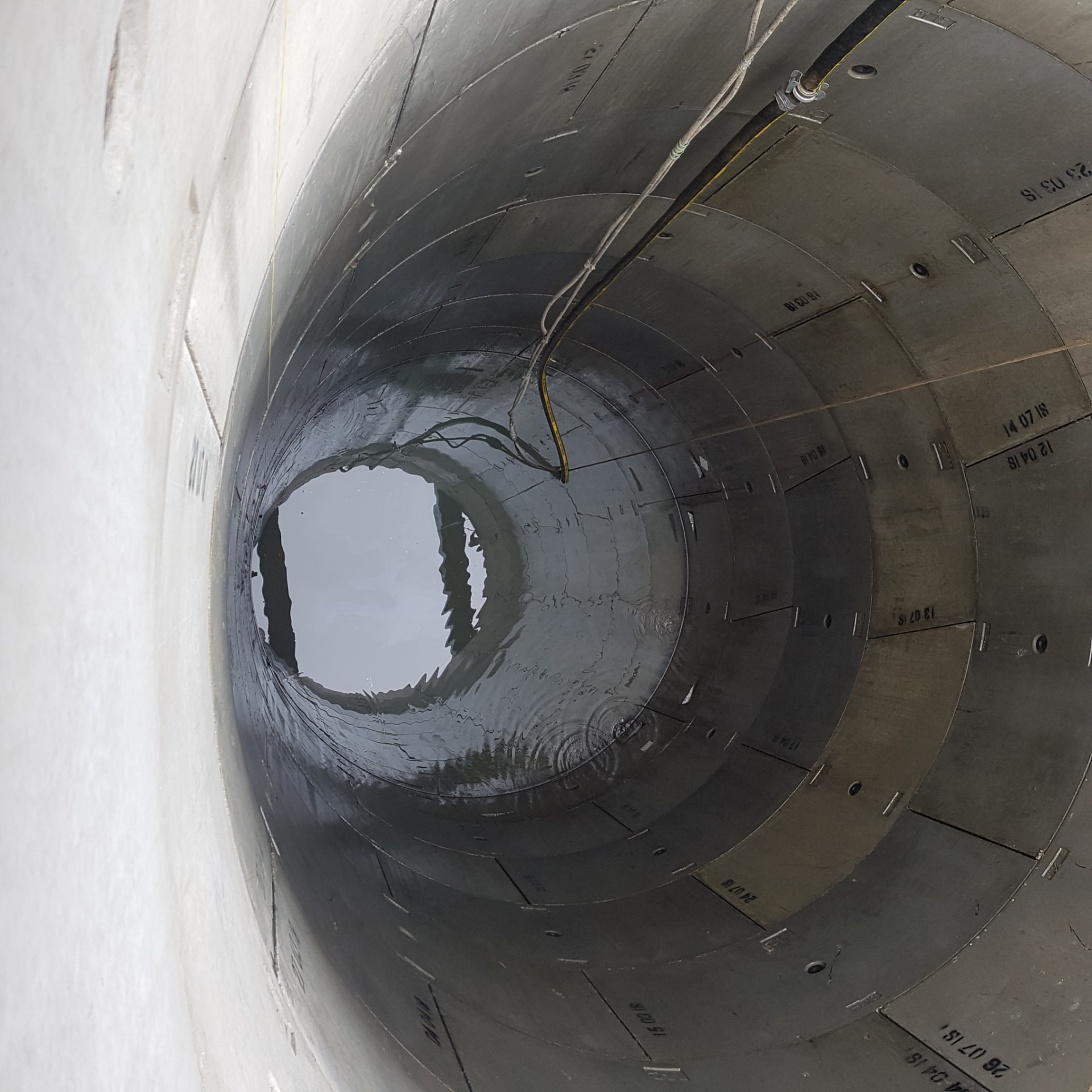 View down a circular shaft lined with bolted precast concrete segment rings